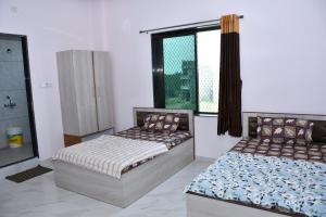 two beds in a room with a window at Hotel Khatushyamji in Rīngas