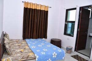 a bedroom with a bed with a blue comforter and a window at Hotel Khatushyamji in Rīngas