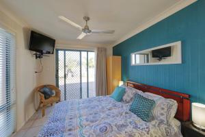 a bedroom with a bed with a blue wall at Golden Cane Bed & Breakfast in Bargara