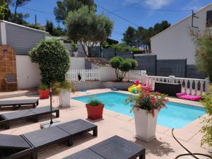 a backyard with a swimming pool with benches and plants at Les Arbousiers in Boulouris-sur-Mer