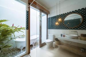 ein Badezimmer mit Badewanne, Waschbecken und Spiegel in der Unterkunft Mermaid Villa Bingin in Bingin Beach