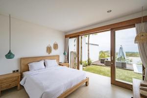 ein Schlafzimmer mit einem Bett und einer Glasschiebetür in der Unterkunft Mermaid Villa Bingin in Bingin Beach