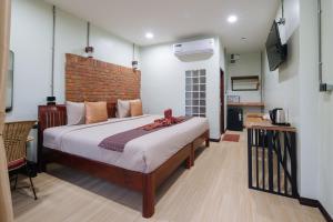 a bedroom with a bed and a television in it at Pongphen Guesthouse - SHA Plus Certified in Kanchanaburi