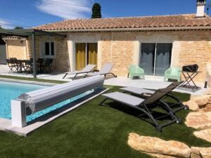 une piscine avec des chaises longues et des chaises à côté d'une maison dans l'établissement Villa Mapokia 2 , climatisée, proche Uzès, 3 étoiles de France, à Saint-Marcel-de-Carreiret