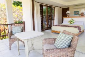 a bedroom with a bed and a table and chairs at Adila Bali in Uluwatu