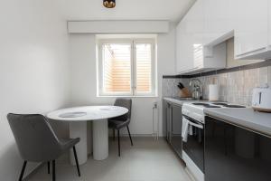 a white kitchen with a small table and chairs at Kotimaailma Aparthotel - Ankkuri - Studio in Kotka