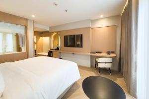 a bedroom with a bed and a desk with a tv at Samsara Hotel Pattaya in Pattaya South +52 photos