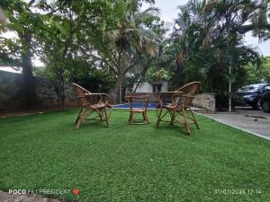 three chairs sitting on the grass in a yard at Varsha's Nest at Uthandi in Chennai