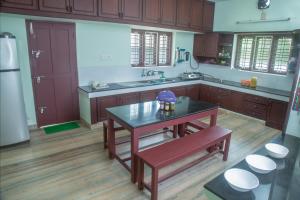 una cocina con armarios de madera y una mesa. en Lake County Heritage Home, en Kochi