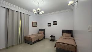 a bedroom with two beds and a chandelier at شقة راقية للايجار اليومي in Taif