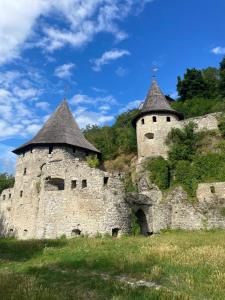 Un antiguo castillo con dos torres en un campo en ПОМЕШКАННЯ на площі Польський ринок, en Kamianets-Podilskyi