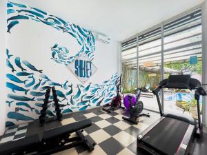 un gimnasio con dos máquinas de correr y un mural en la pared en Sujet Beach Hotel and Apartment Danang by Haviland, en Da Nang