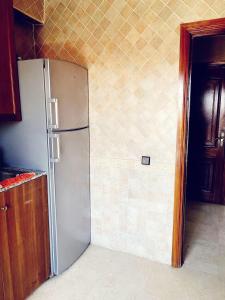 lodówka ze stali nierdzewnej w kuchni obok ściany w obiekcie Bel appartement 2 chambres au cœur de Marrakech w mieście Oulad Akkou