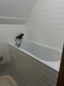 El baño incluye bañera con grifo negro. en High mountain Apartment, en Vyshka