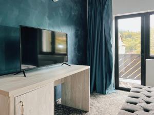 a living room with a flat screen tv on a entertainment center at Suru Hotel & Restaurant in Buşteni +10 photos