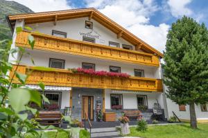 a large white building with a wooden balcony at Vermunt - Silvretta Sommer Premium Card inklusive in Galtür