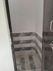 a bathroom with a shower with a tiled floor at Sarvgun Apartment in Jāmb