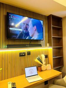 Un televisor en una pared con una computadora portátil sobre una mesa. en Muffin Stays, en Ghaziabad