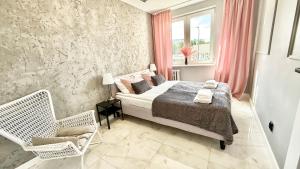 a bedroom with a bed and a chair and a window at Apartment Seaside Jelitkowo in Jelitkowo