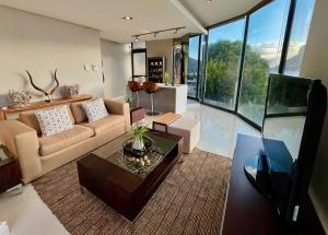 a living room with a couch and a table at The Leopard Rock Suite with uninterrupted beach views in Hout Bay