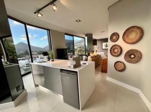 a kitchen with a counter and some windows and a couch at The Leopard Rock Suite with uninterrupted beach views in Hout Bay +19 photos