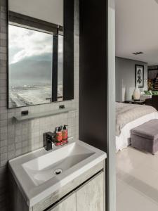 a bathroom with a white sink and a bed at The Leopard Rock Suite with uninterrupted beach views in Hout Bay
