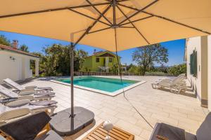 un patio con ombrellone e sedie e una piscina di Holiday house VILLA ANTON with private pool a Kras