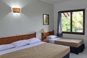 pokój hotelowy z 2 łóżkami i oknem w obiekcie Hotel Winotosastro Garden w mieście Yogyakarta