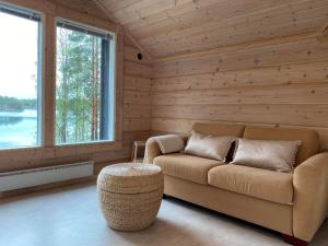 a living room with a couch and a table and windows at Hideout Villa Hilikkula in Rokua