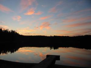 a sunset over a lake with a wooden dock at Hideout Villa Hilikkula in Rokua
