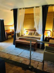 - une chambre avec un lit avec des rideaux et une table dans l'établissement Appartement - LES COMBLES DU CHATEAU DES MARAIS - Avec vue sur le lac - POUR 2 à 5 PERSONNES, à Saint-Philbert-de-Grand-Lieu