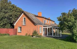 an orange house with a red fence in a yard at Amazing Apartment In Tranekær With Wifi in Stoense +12 photos