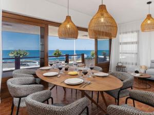 Un comedor con mesa y sillas y el océano. en KARAT Villa Bajamar, en El Puertito