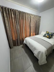 a bedroom with a bed and a window with curtains at Mykwas Apartments in Naledi