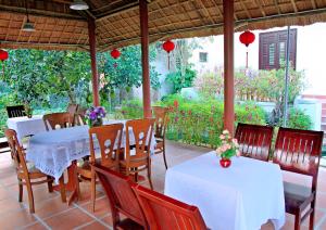 a restaurant with white tables and chairs and red lanterns at Countryside Garden Homestay in Hoi An