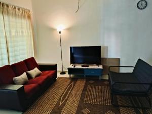 a living room with a red couch and a chair at Homestay Payung Merah Islam Sahaja in Simpang Empat