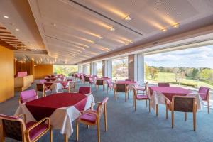 Un comedor con mesas y sillas y grandes ventanales. en Nasu Chifuriko Country Club, en Nasu