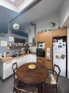 a kitchen with a wooden table and a refrigerator at Maison de ville jardin derrière cité U à Gentilly in Gentilly
