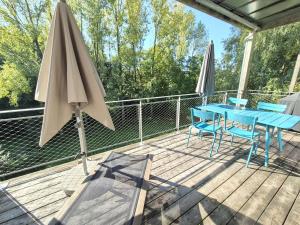 ein blauer Tisch und Stühle auf einer Terrasse mit einem Sonnenschirm in der Unterkunft Maison "Chalet Concept" 6 pers à 10min Puy du Fou in La Gaubretière