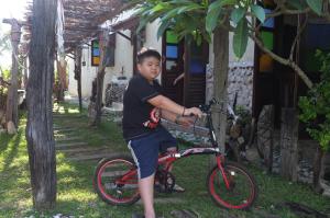 关丹圣帕海滩乡村旅馆的一名小男孩在房子前面骑着自行车