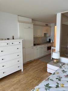 Una cocina con gabinetes blancos y una cómoda blanca. en Studio avec accès direct au lac de Geneve, en Saint-Gingolph