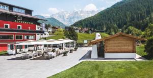 a resort with tables and chairs and a building at Hotel Alpenroyal - The Leading Hotels of the World in Selva di Val Gardena