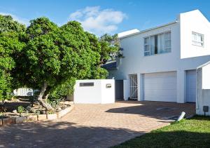 a white house with a tree and a garage at 1 bedroom cottage south of Cape Town in Marina Da Gama +12 photos