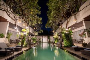 einen Innenpool mit Stühlen und Bäumen in einem Gebäude in der Unterkunft Swiss-Belcourt Sunset in Seminyak