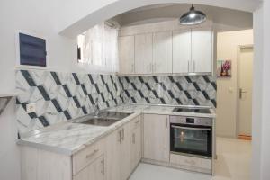 a kitchen with white cabinets and a sink and an oven at Villa Eleni Holidays Resort - with Pool near the Beach in Sidari