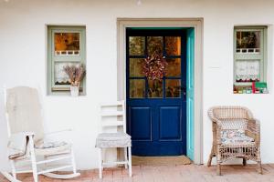 a blue door on a white house with two chairs at Kiskovász Pajta & Inn in Nagytevel