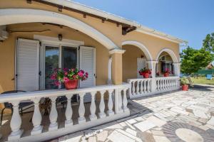 a house with a white railing and flowers on the balcony at Villa Eleni Holidays Resort - with Pool near the Beach in Sidari
