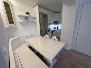 una pequeña cocina con mesa blanca y sillas en White Apartment, en Peio Fonti