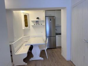 Una pequeña cocina con una mesa y un refrigerador. en White Apartment, en Peio Fonti