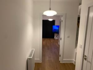 a hallway with a white door and a room with a blue object at 4Bed House - Direct links into Central London in North Ockendon